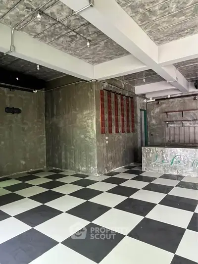 Spacious industrial-style interior with checkered flooring and exposed ceiling.