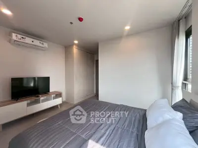 Modern bedroom with sleek design, featuring a cozy bed, TV, and ample natural light.