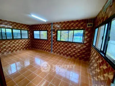 Spacious room with unique geometric tiled walls and large windows for natural light.
