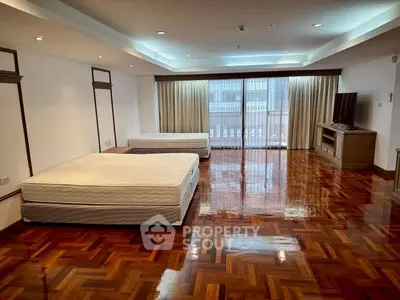 Spacious bedroom with polished wooden floors and large windows in a modern apartment.