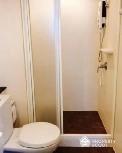 Compact bathroom with shower and toilet in modern apartment.