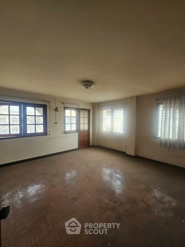 Spacious empty room with large windows and wooden flooring, ideal for customization.