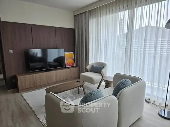Modern living room with stylish furniture and large window offering natural light.