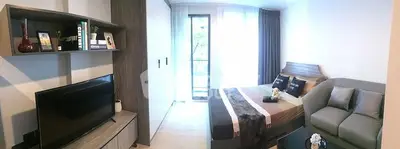 Modern bedroom with cozy decor and natural light, featuring a TV and stylish shelving.