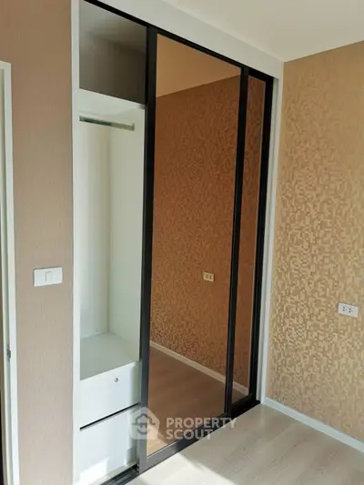 Modern bedroom with sleek mirrored closet doors and stylish wallpaper.