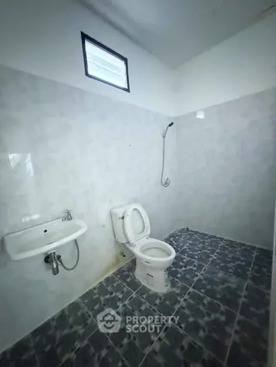 Minimalist bathroom with tiled floor and wall-mounted shower in a real estate property.