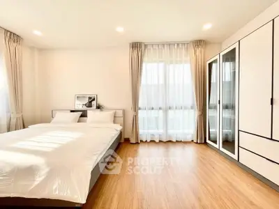 Spacious and bright bedroom with modern decor and large windows.