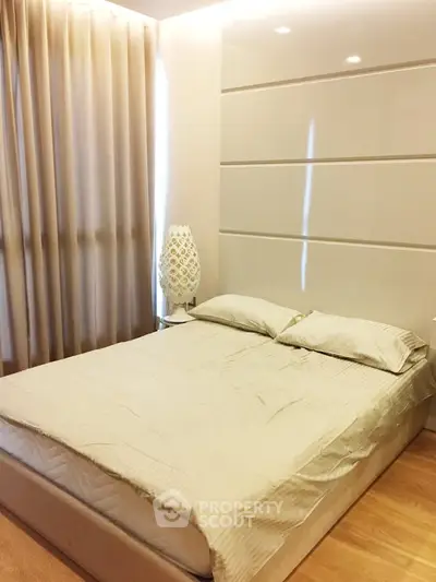 Modern bedroom with elegant decor and soft lighting, featuring a comfortable bed and stylish lamp.