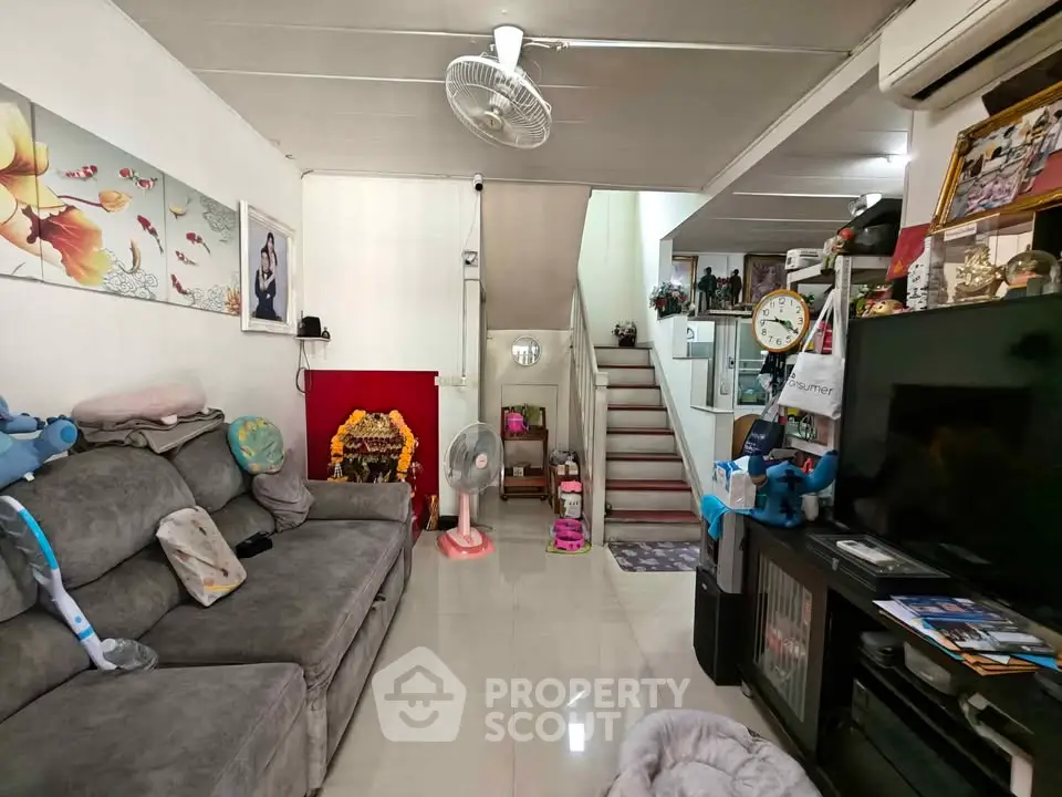 Cozy living room with modern decor and staircase, featuring a comfortable sofa and wall art.