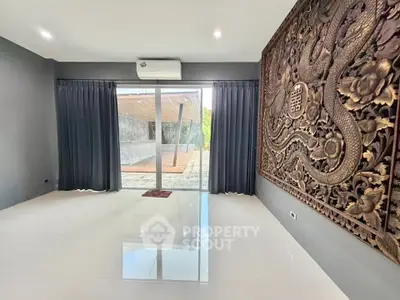 Spacious modern room with large carved wall art and sliding glass doors to patio.