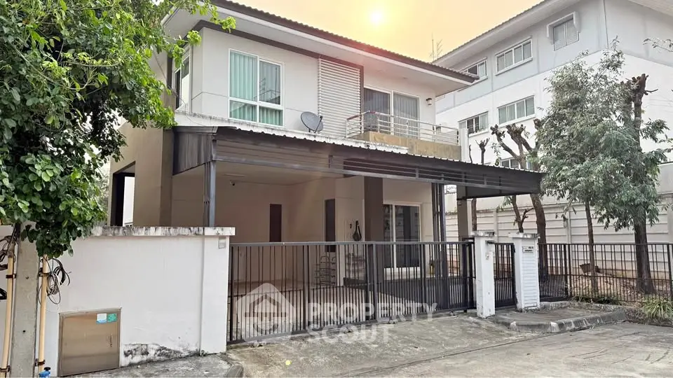 Modern two-story house with gated driveway and balcony in a serene neighborhood.