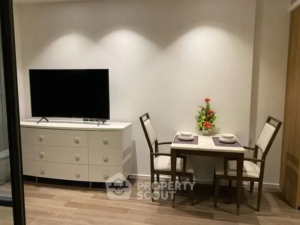 Cozy living room with modern TV setup and elegant dining area for two.