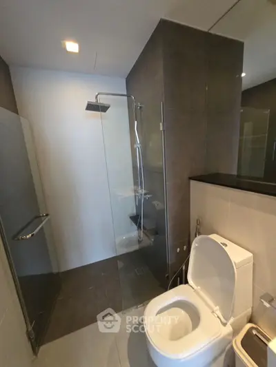 Modern bathroom with glass shower and sleek fixtures in contemporary apartment.