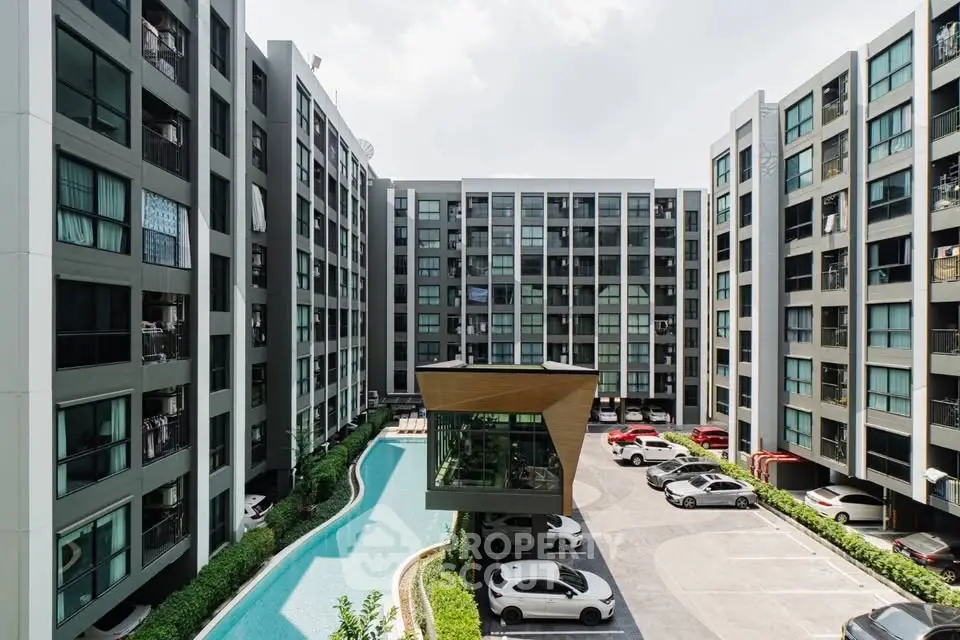 Modern apartment complex with pool and parking area, showcasing urban living.