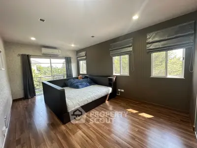 Spacious bedroom with large windows and wooden flooring