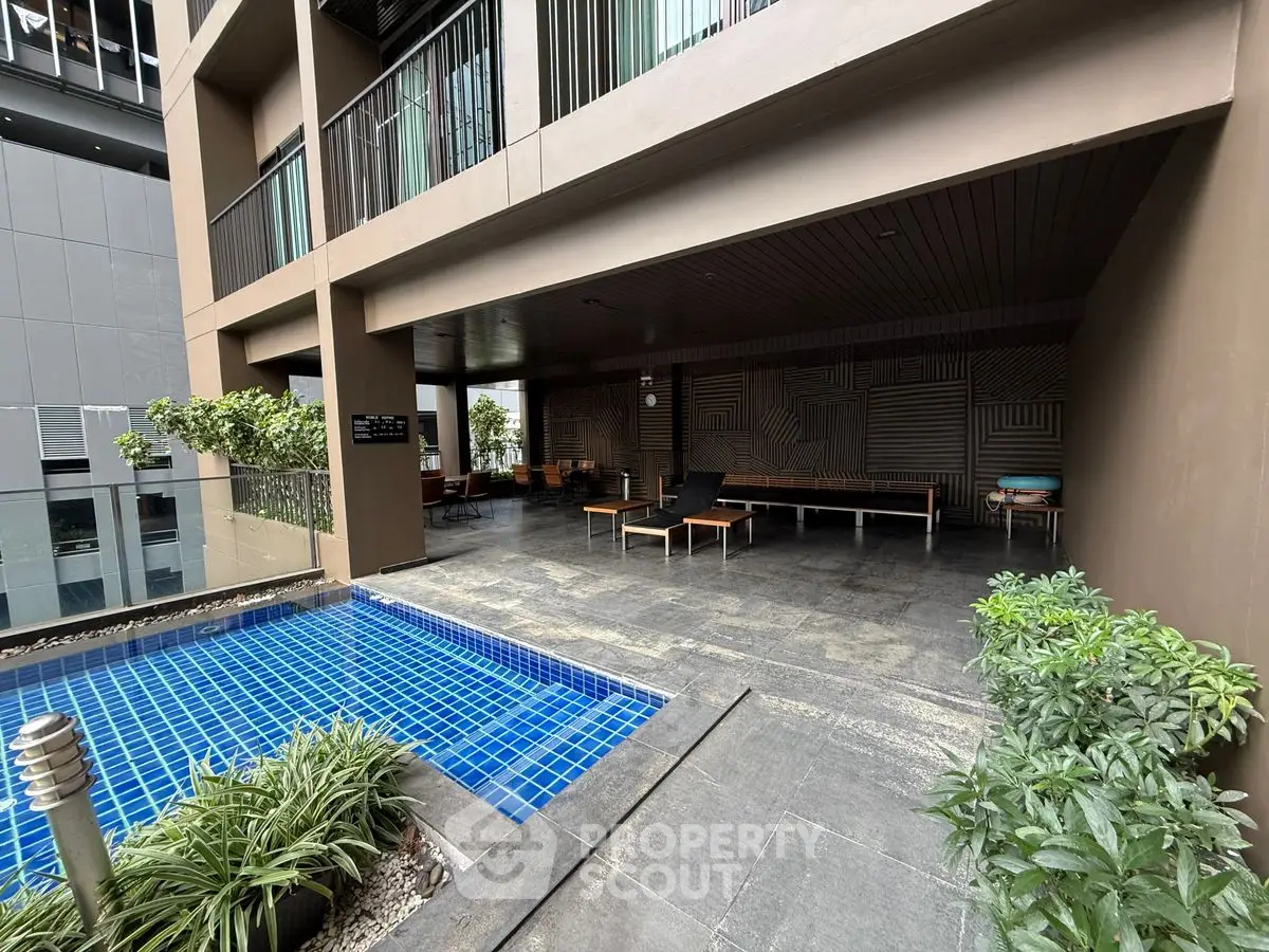 Modern apartment building with poolside lounge area and stylish design.