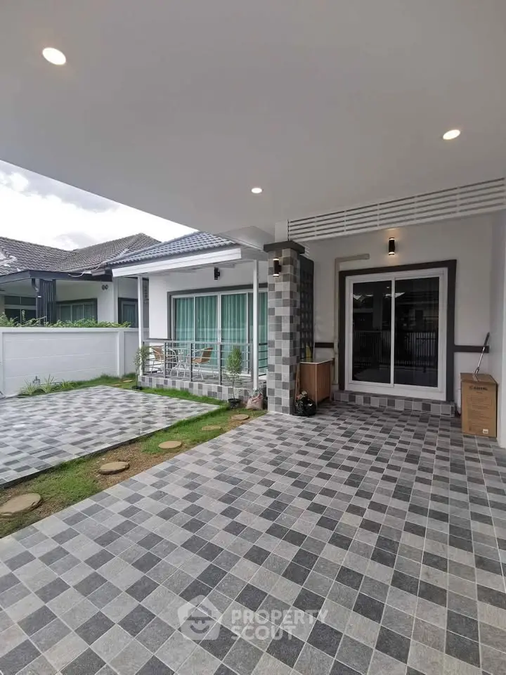Modern house exterior with spacious tiled patio and sliding glass doors, perfect for outdoor living.