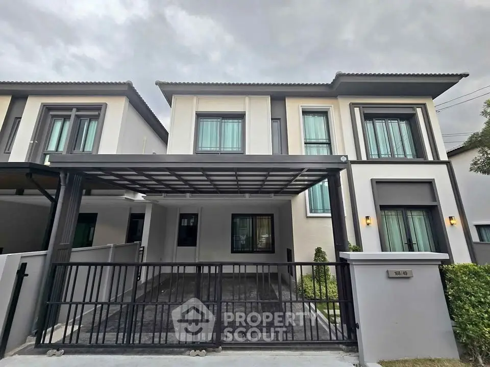 Modern two-story house with sleek facade and gated driveway in suburban neighborhood.