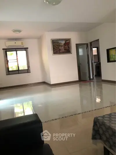 Spacious living room with tiled flooring and natural light, featuring modern decor and air conditioning.
