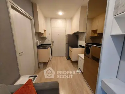Modern compact kitchen with sleek appliances and cozy living area in stylish apartment.