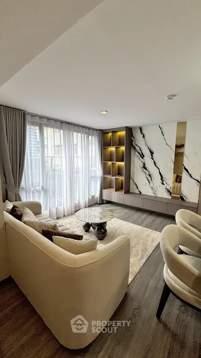 Luxurious modern living room with elegant marble accent wall and cozy seating area.