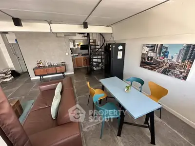 Stylish open-plan living room with modern furniture and spiral staircase in urban apartment.