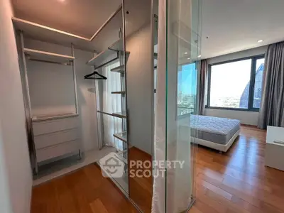 Spacious bedroom with walk-in closet and city view, featuring modern design and natural light.