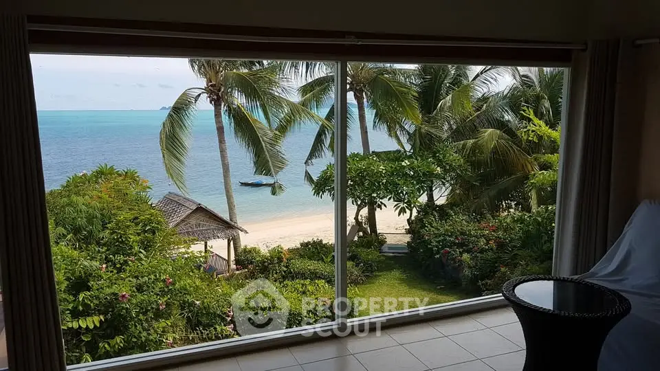Stunning beachfront view from a luxurious property with lush greenery and serene ocean.
