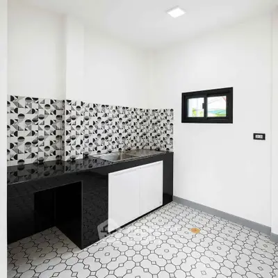Modern kitchen with geometric tile backsplash and sleek black countertops.