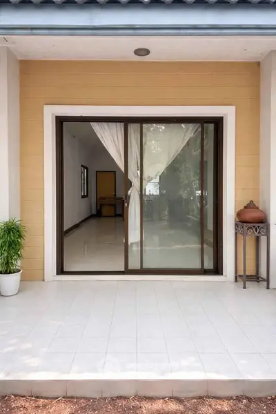 Charming home entrance with sliding glass doors and tiled patio, perfect for indoor-outdoor living.