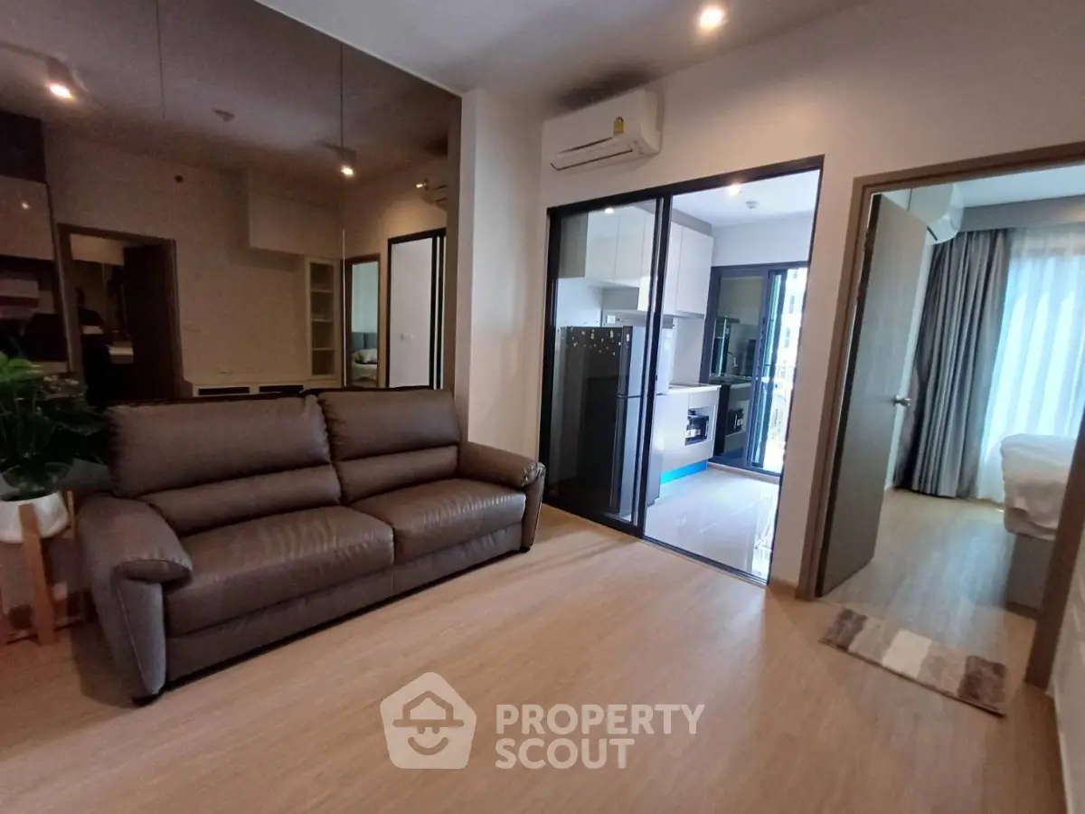 Modern apartment interior with cozy living room and open kitchen layout, featuring sleek design and ample natural light.