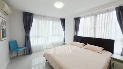 Spacious bedroom with large windows and elegant curtains in modern apartment.