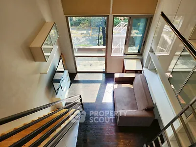 Modern loft-style living room with large windows and stylish staircase