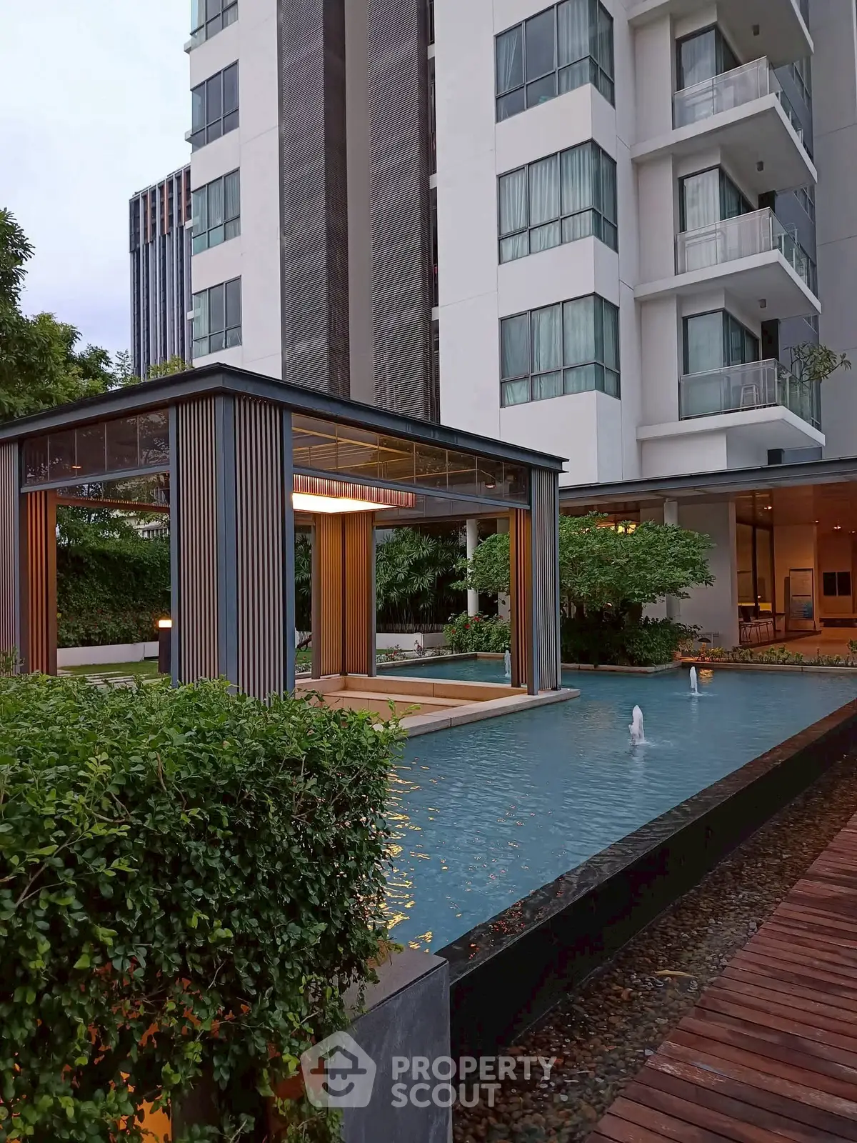 Modern apartment building with elegant water feature and lush greenery