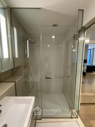Modern bathroom with glass shower enclosure and sleek fixtures in a contemporary apartment.