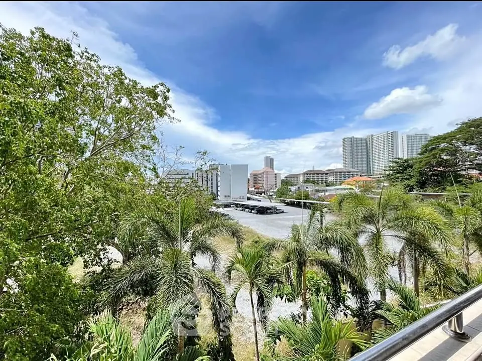 Stunning cityscape view from a balcony with lush greenery and skyline backdrop.