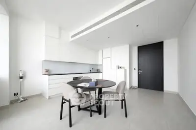 Modern minimalist kitchen with sleek white cabinetry and round dining table.