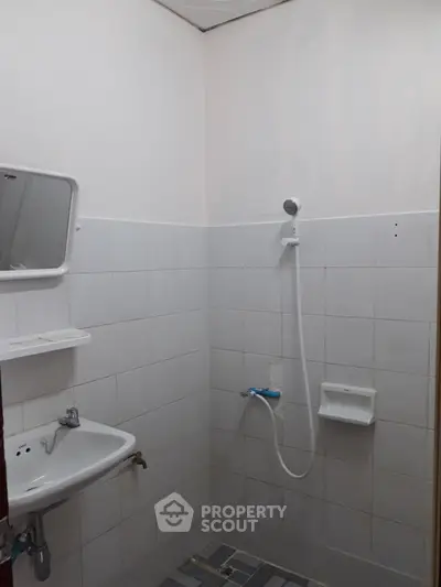 Compact bathroom with white tiles and basic shower setup