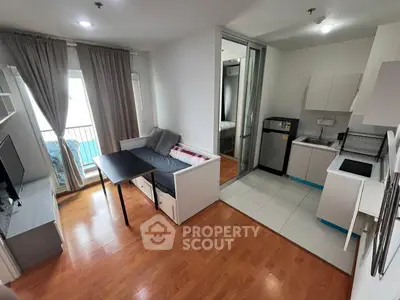 Modern open-plan living room with kitchen and balcony access, featuring sleek furniture and natural light.