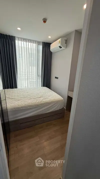 Modern bedroom with large window and air conditioning in a stylish apartment.