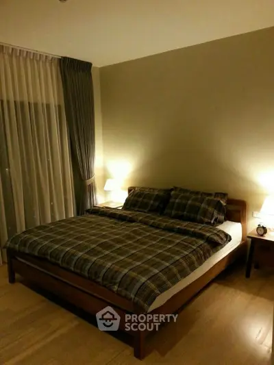 Cozy bedroom with warm lighting and plaid bedding in modern apartment.