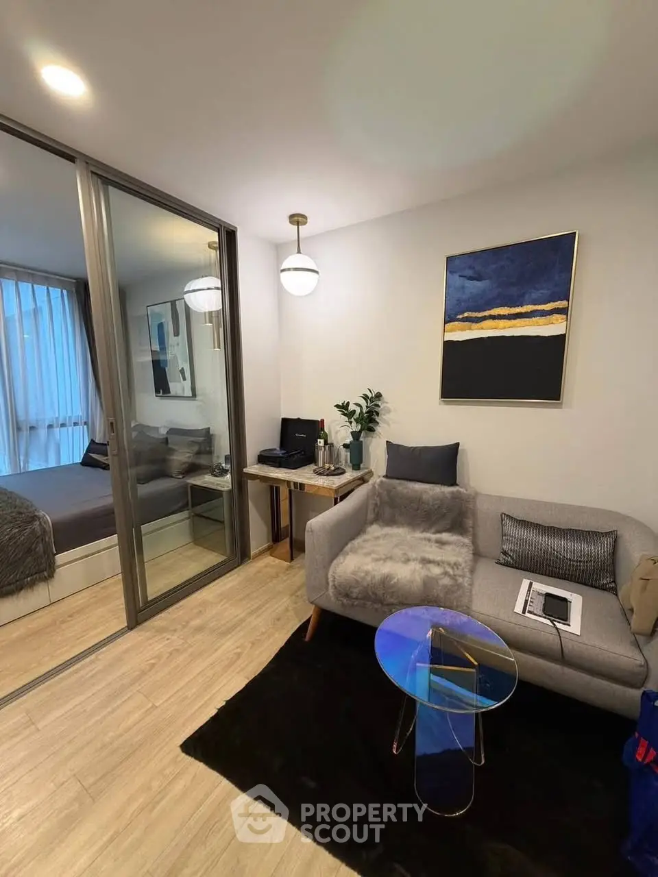 Modern living room with cozy sofa and stylish decor adjacent to a bedroom with glass sliding doors.