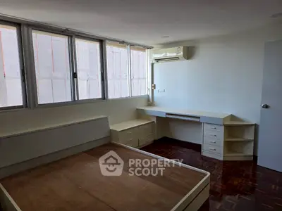 Spacious bedroom with built-in desk and large windows for natural light.