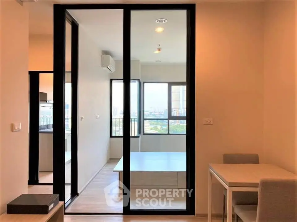 Modern apartment interior with sliding glass doors and city view, featuring a cozy dining area and bright living space.