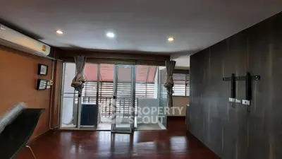 Spacious living room with wooden flooring and balcony access in modern apartment.