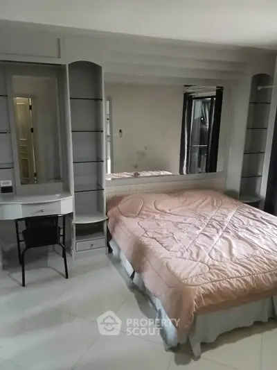 Spacious bedroom with elegant decor and large mirror, featuring a cozy bed and sleek furniture.