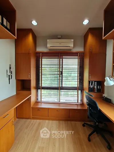 Spacious study room with built-in wooden shelves and large window view
