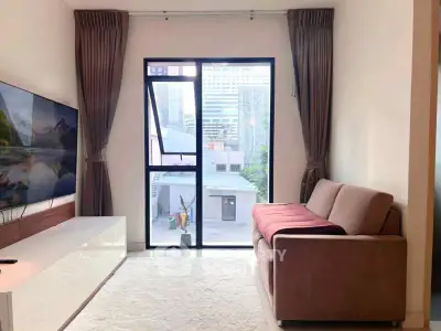 Modern living room with large window and city view, featuring a sleek sofa and flat-screen TV.