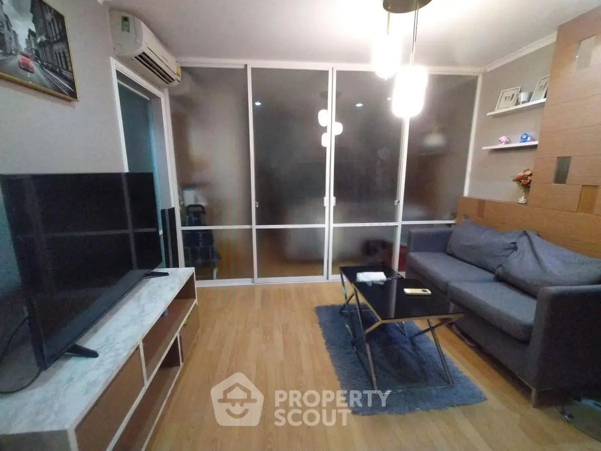 Modern living room with sleek design, featuring a large TV, comfortable sofa, and stylish lighting.