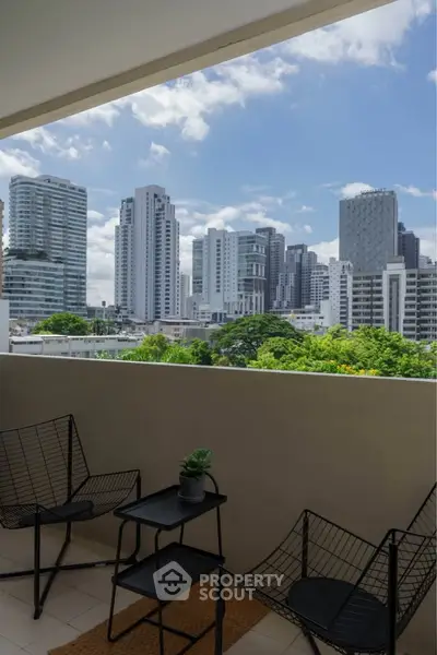 Modern balcony with city skyline view, featuring stylish outdoor furniture and lush greenery.